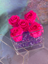 Clear acrylic cube box with drawer, featuring four hot pink preserved roses on top and purple crystal accents inside.