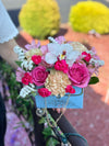 Light blue Bloom de Fleur purse box filled with pink roses, peach carnation, white orchid and filler flowers